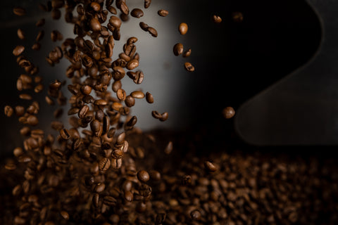 La Prima Espresso Company - Home Page -Close up image of beans falling into cooling tray of a coffee roaster. Vibe is clean and minimalist.